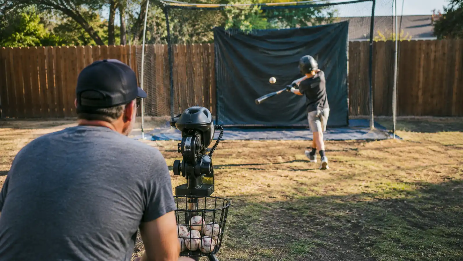 Young baseball player taking a swing at a pitching machine in a backyard batting setup
