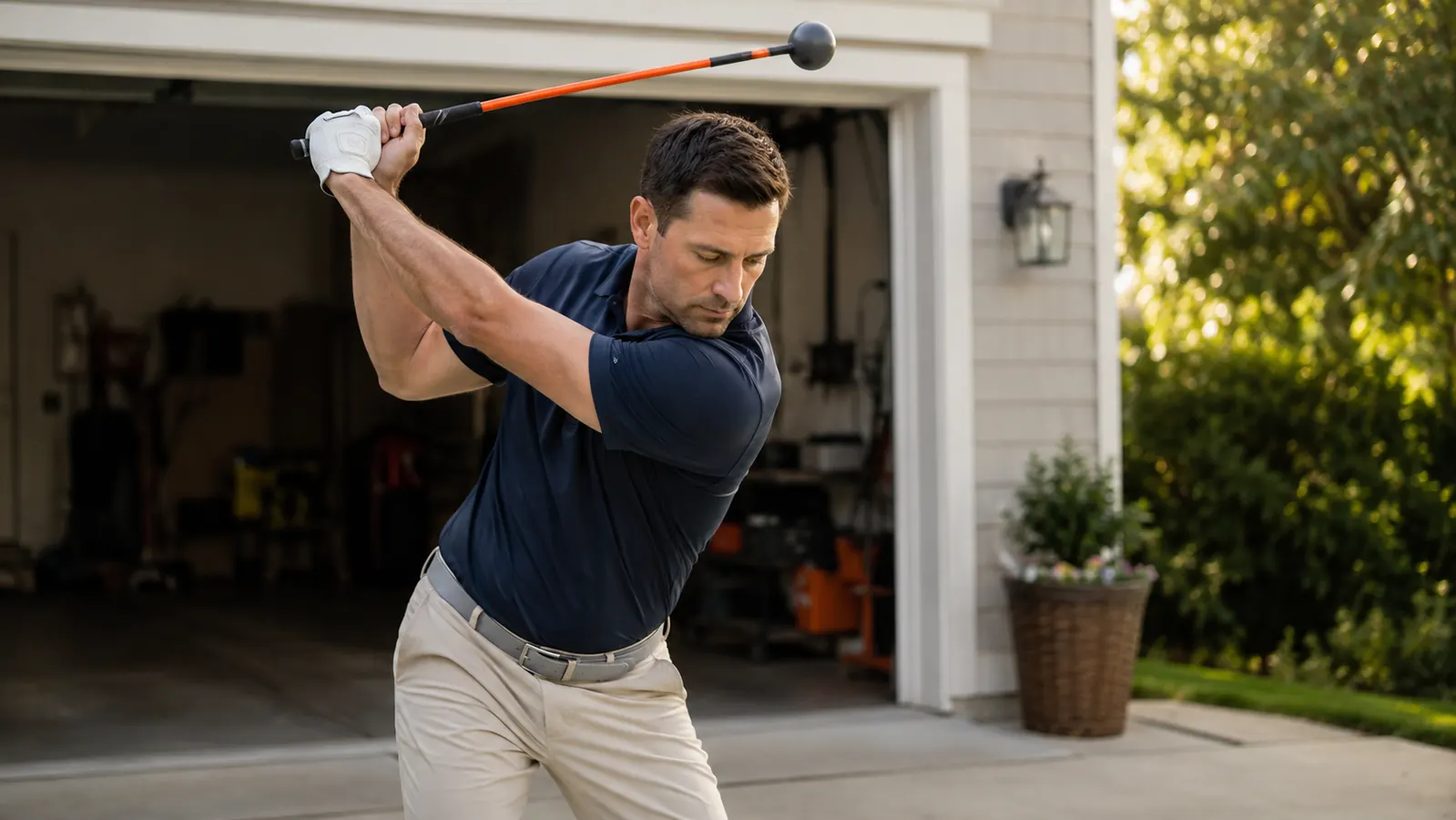 Weekend golfer counting out loud mid-backswing with an orange-shafted swing trainer in a driveway