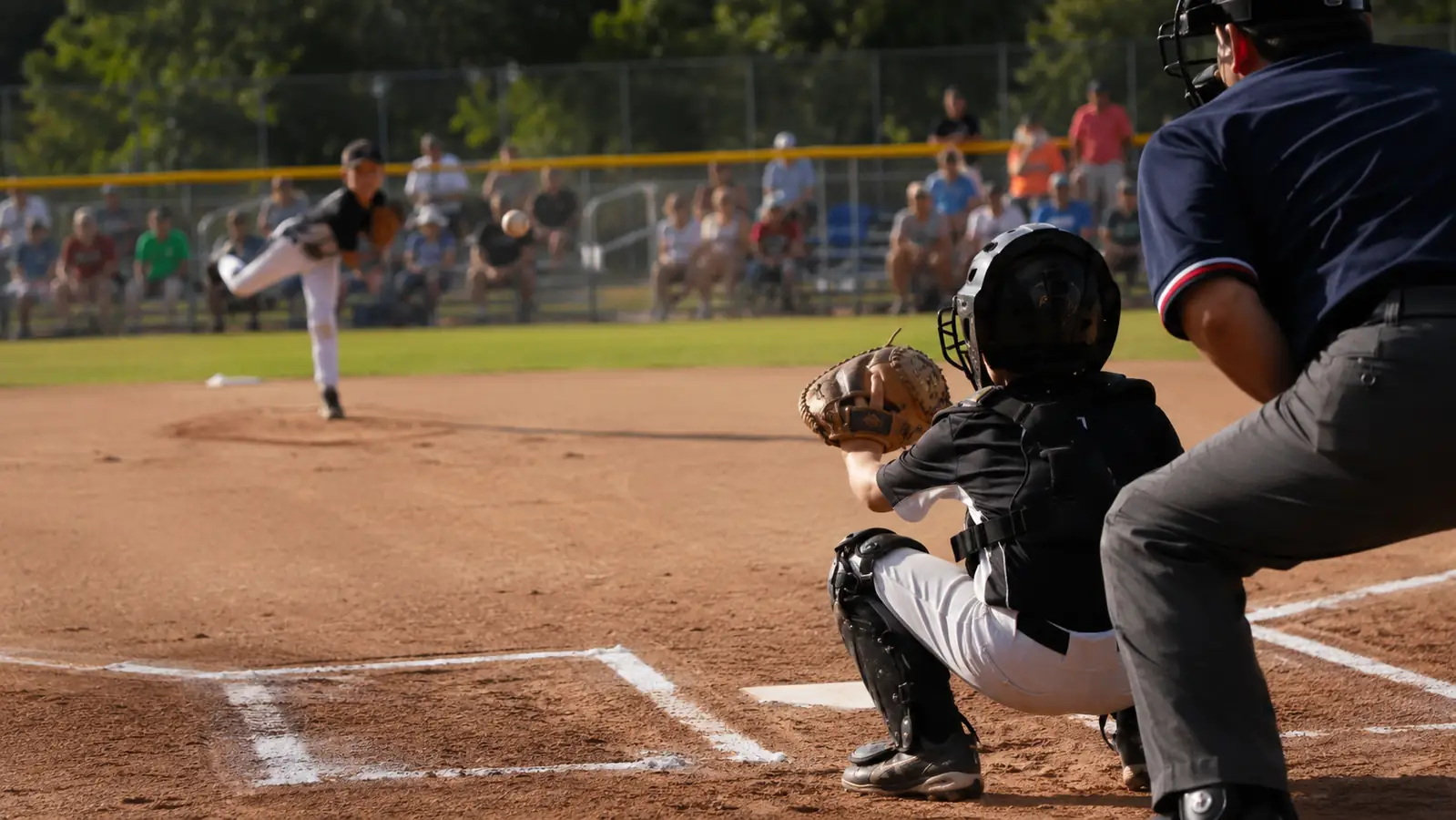 Ten-year-old catcher in navy and red gear crouched behind home plate at a spring rec-league field