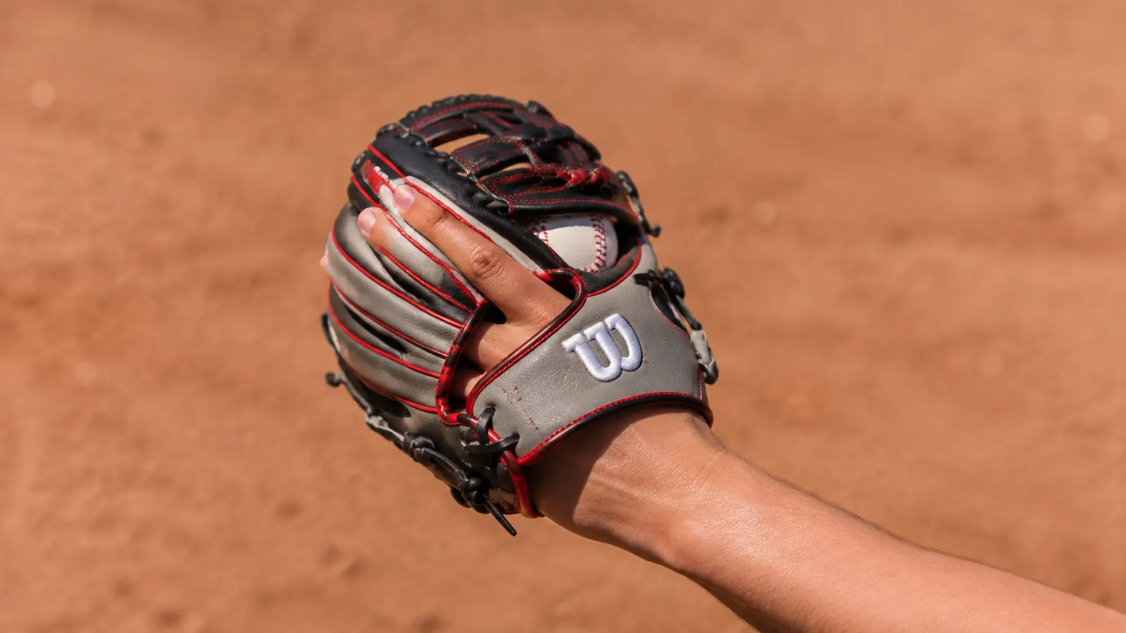 A hand wearing the Wilson A2000 glove closing around a baseball in the pocket